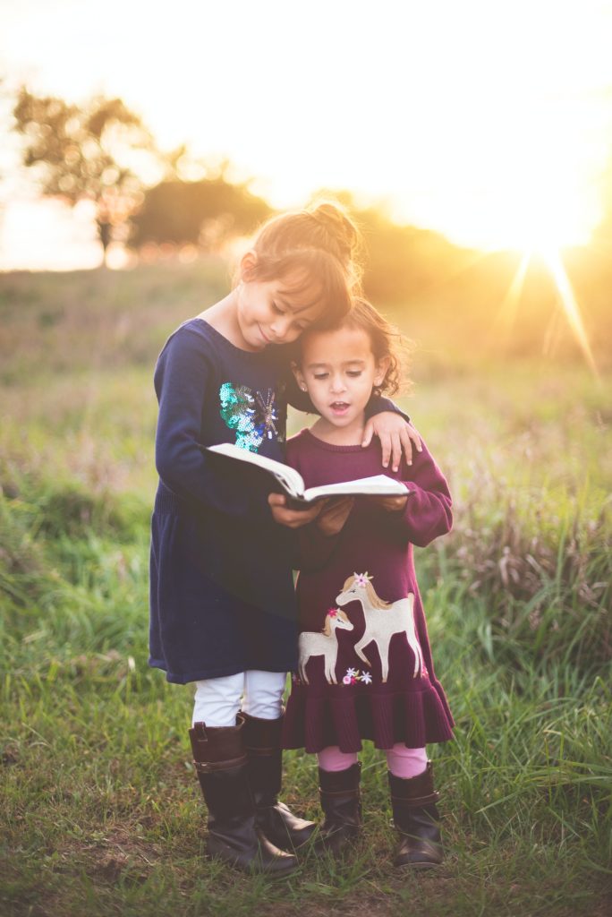 Two girls embracing each other and reading a book